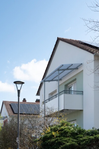 Modernes Haus mit Solarzellen und Balkon im Sonnenschein.