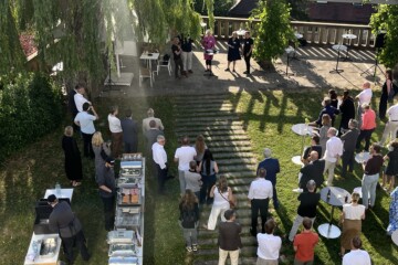 Teilnehmer beim Strategiedialog-Sommerfest im Garten, Gespräche und Networking im Freien.