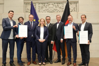 Gruppenfoto beim Strategiedialog mit Unterzeichnern und Flaggen.